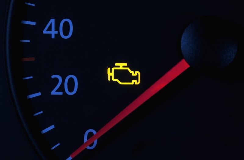 A yellow, check-engine light on a car dashboard indicating a possible problem.